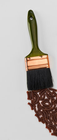 A paintbrush is used to spread a trail of dark coffee beans across a plain white background, creating a unique texture.の写真素材