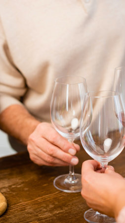 Two people's hands are shown holding wine glasses, about to clink them together in a celebratory toast.の写真素材