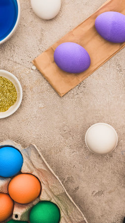 Overhead view of vibrant Easter eggs in various colors being prepared for decoration on a textured...