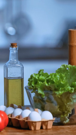 A collection of fresh ingredients including lettuce, eggs, oil, and a tomato, ready for cooking.の写真素材