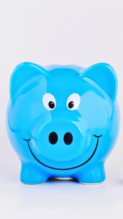 A vibrant blue ceramic piggy bank shaped like a pig with a wide smile and big eyes, perfect for saving coins.の写真素材