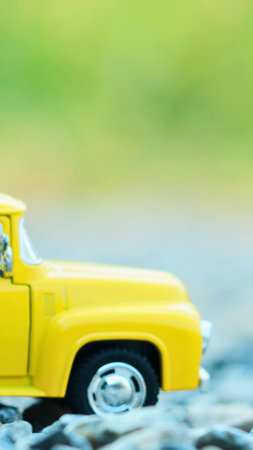 A close-up, side view of a miniature yellow pickup truck with a blurred green background.の写真素材