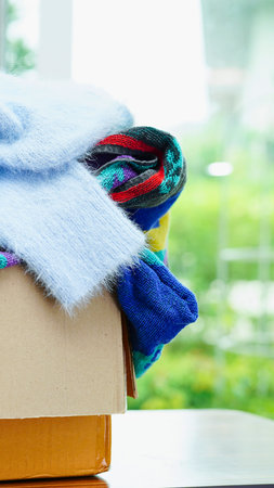 A stack of colorful laundry rests on a light surface, with a blurred green outdoor scene visible through a window.の写真素材