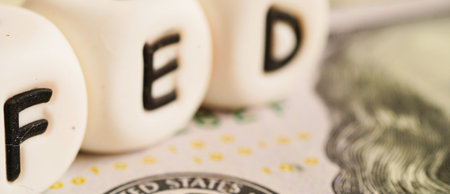 Close-up view of white blocks spelling 'FED' resting on a US dollar bill, symbolizing monetary policy and finance.の写真素材