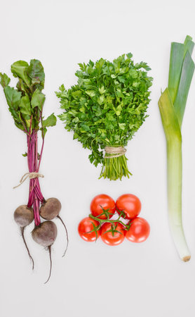 A vibrant assortment of fresh vegetables including beets parsley tomatoes and a leek arranged on a...