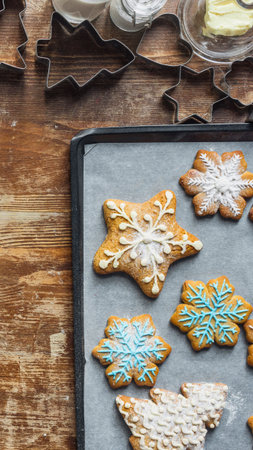 A close-up overhead view of star-shaped cookies with intricate icing designs, arranged on a baking sheet with a rustic wooden background.の写真素材