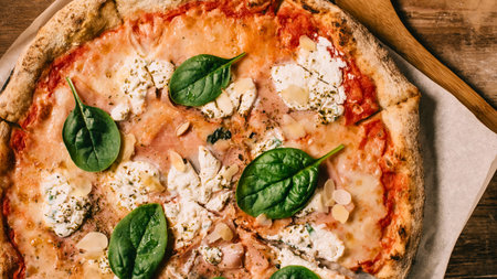 A close-up overhead view of a freshly baked Margherita pizza with melted mozzarella, vibrant tomato sauce, and fresh basil leaves.の写真素材