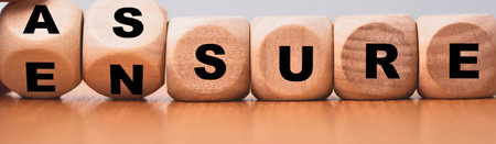 Close-up of wooden blocks with letters spelling out the word ASSURE, set on a wooden surface.の写真素材