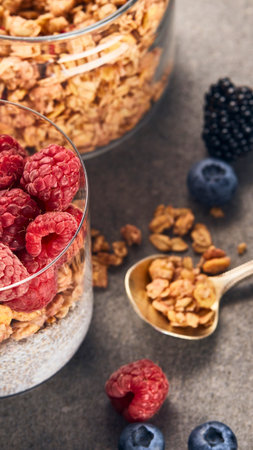 A close-up shot of crunchy granola, fresh raspberries, blueberries, and blackberries, hinting at a nutritious and flavorful start to the day.の写真素材