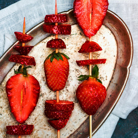 Sweet strawberry skewers with chocolate drizzle are artfully arranged on a decorative platter, a delightful and refreshing treat.の写真素材