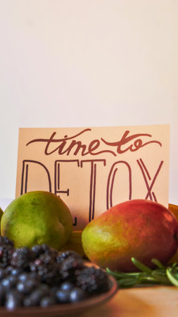 A vibrant arrangement of fresh fruits including mangoes and blueberries, with a hand-lettered sign promoting detoxification and healthy eating.の写真素材