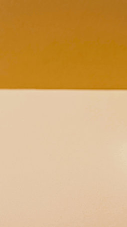 A minimalist abstract image featuring a distinct horizontal line dividing a warm mustard yellow top from a soft, light beige bottom.の写真素材