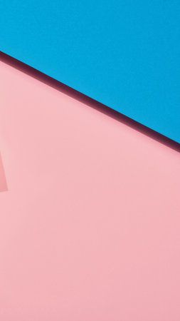 A minimalist abstract image featuring two distinct geometric planes, one a soft pink and the other a vibrant blue, meeting at a sharp diagonal line.の写真素材