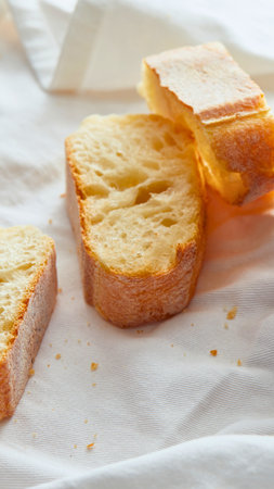 Golden brown toasted bread slices are artfully arranged on a textured white cloth, creating a simple yet inviting still life.の写真素材