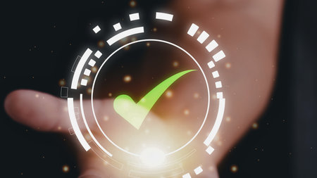 A glowing green checkmark appears within a futuristic circular interface projected onto a person's open palm.の写真素材