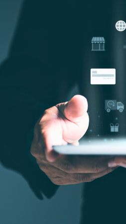 A person's hand gently holds a modern digital device, its screen emitting a soft, bright glow against a dark background.の写真素材