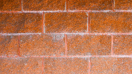 A textured, close-up view of a red brick wall showing the rough surface of the bricks and the white grout lines between them.の写真素材