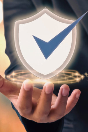 A hand cradles a luminous shield with a checkmark, representing safety, verification, and successful protection in a digital or physical context.の写真素材