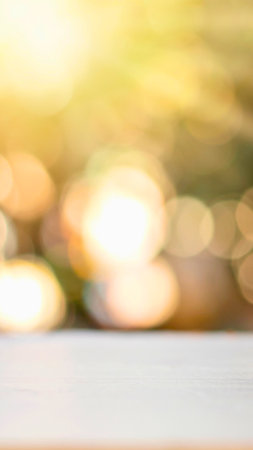 Abstract background with warm, blurred golden bokeh lights and a clean white surface in the foreground.の写真素材
