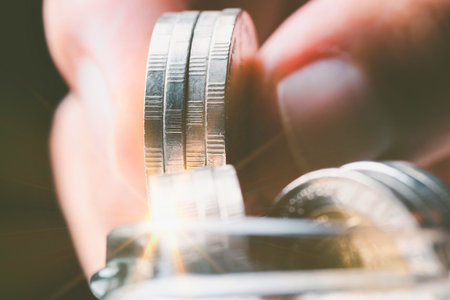 A person's fingers are holding two intricately designed silver rings, one above the other, in a close-up shot.の写真素材