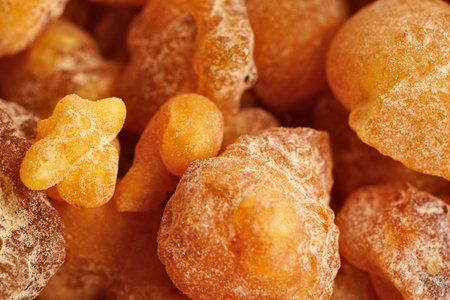 Macro view of natural amber resin chunks showing their translucent, irregular forms and warm orange hues.の写真素材