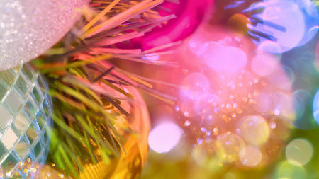 A festive, abstract close-up of a decorated Christmas tree featuring pine needles, ornaments, and soft, blurred bokeh lights.の写真素材