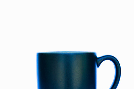 A simple, dark blue ceramic mug with a handle is shown in a close-up studio shot against a stark white background.の写真素材