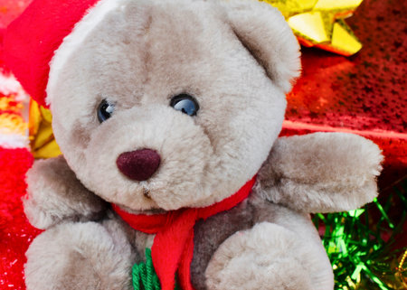 A close-up of a fluffy gray teddy bear with a red scarf, surrounded by brightly colored, wrapped presents.の写真素材