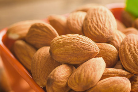 A macro shot showcases a heap of raw almonds, their ribbed shells prominent and inviting, hinting at their natural goodness.の写真素材