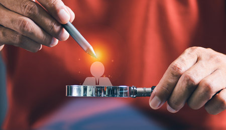 Close up of hands using a magnifying glass to examine a glowing person icon, symbolizing focus and analysis.の写真素材