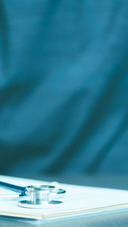 A close-up shot of a stethoscope resting on a medical chart, with a blurred teal background.の写真素材