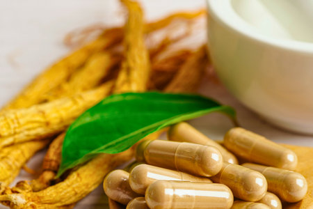 A close-up of dried ginseng roots and a pile of herbal capsules, suggesting natural health and wellness products.の写真素材