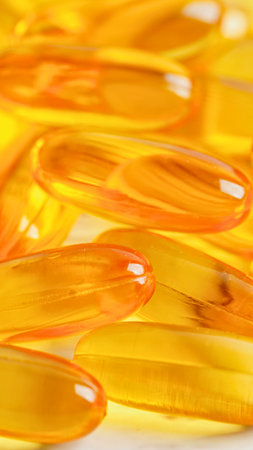 A macro view of numerous oval-shaped, translucent orange gel capsules, creating a textured and vibrant background.の写真素材