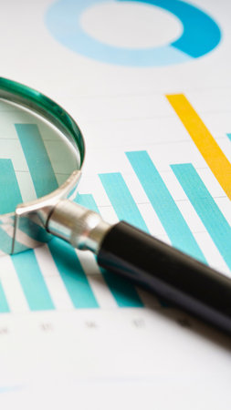 A magnifying glass is placed over a financial chart, highlighting bars and data analysis. The image suggests business research and investigation.の写真素材
