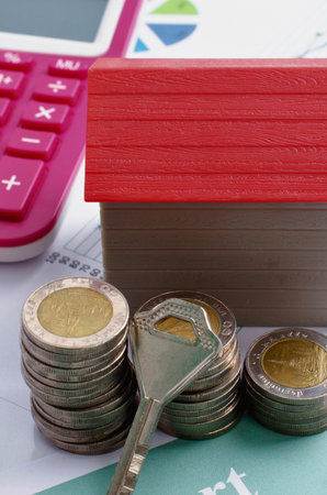A conceptual image representing real estate investment, home ownership, and financial planning with a house model, coins, and a key.の写真素材