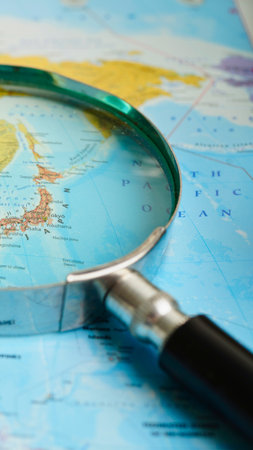 A magnifying glass is positioned over a colorful world map, highlighting specific regions and details for exploration.の写真素材