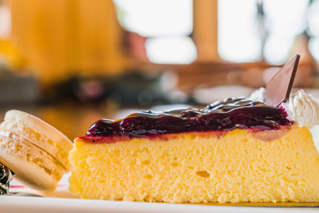 A close-up shot of a creamy cheesecake slice topped with blueberry compote, ready to be enjoyed with a fork.の写真素材
