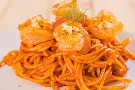 A close-up shot of a generous portion of spaghetti topped with succulent shrimp and a vibrant, creamy tomato sauce.の写真素材