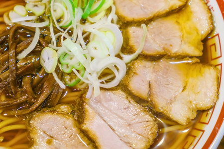 A close-up shot of a steaming bowl of ramen, featuring succulent chashu pork, noodles, and vibrant...