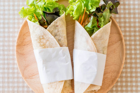 Two delicious and healthy vegetarian wraps filled with fresh lettuce and vegetables, presented on a rustic wooden board.の写真素材
