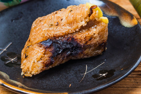 A close-up of a perfectly cooked piece of food, seasoned with herbs, served on a rustic dark plate.の写真素材