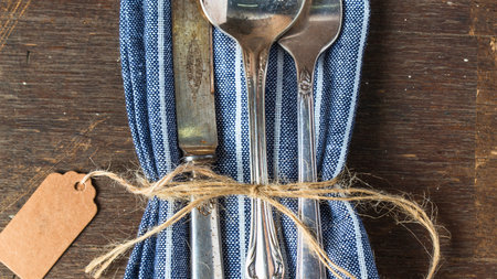 A close-up of two metal utensils wrapped in a blue and white striped cloth, tied with twine and a small brown tag.の写真素材