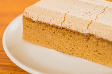A detailed view of a single slice of cake, showcasing its texture and light colored topping on a white plate.の写真素材