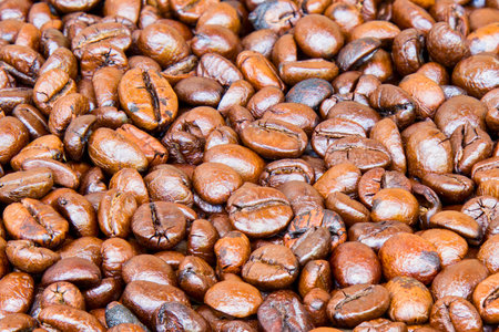 A detailed, overhead shot showcasing a dense pile of freshly roasted coffee beans, highlighting their textured surfaces and warm brown coloration.の写真素材