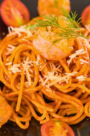 A close-up shot of a steaming plate of spaghetti topped with rich tomato sauce, grated cheese, and fresh dill, garnished with tomato slices.の写真素材