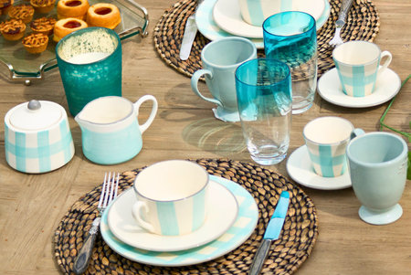 A beautifully arranged table setting features pastel colored mugs, saucers, and a festive platter of appetizers, ready for a delightful gathering.の写真素材