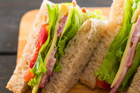 Close-up of stacked club sandwich triangles, showcasing layers of lettuce, tomato, and meat on whole wheat bread.の写真素材