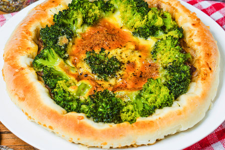 A close-up overhead view of a savory tart filled with vibrant green broccoli florets and melted cheese, baked to a golden perfection.の写真素材