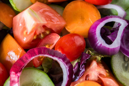 A vibrant close-up of chopped tomatoes, red onions, cucumbers, and other fresh ingredients ready for a delicious salad.の写真素材
