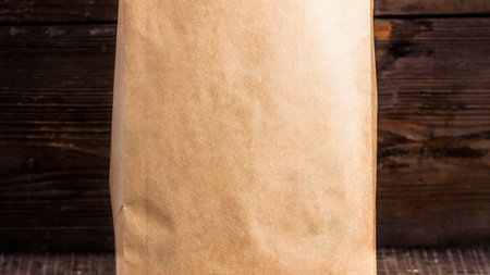 A detailed view of a light brown paper bag's textured surface, set against a dark wooden backdrop.の写真素材
